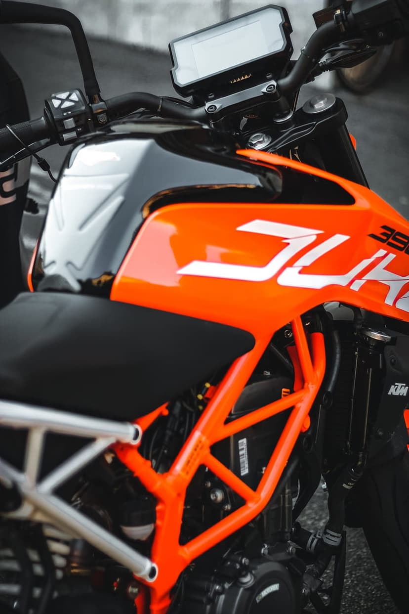 KTM 390 Duke motorcycle featuring an orange trellis frame, black seat, and digital dash in a vertical view.