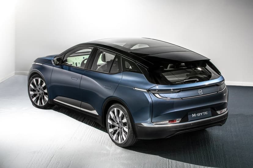 Rear view of a sleek dark blue Byton M-Byte electric SUV with a glass roof in a bright white studio.