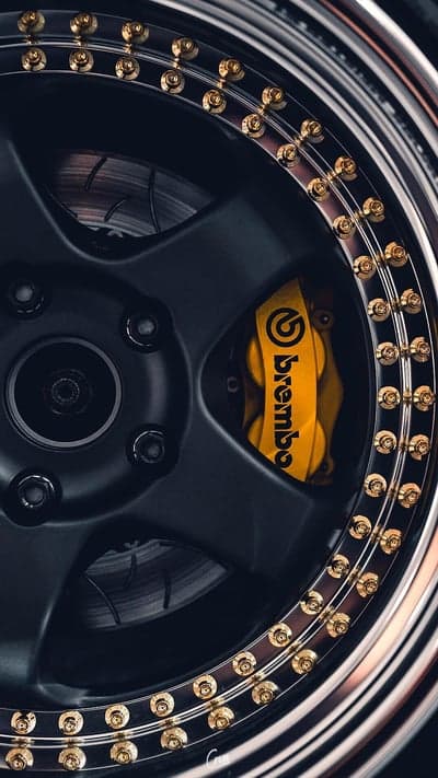 Close-up of black wheel with gold bolts and yellow Brembo