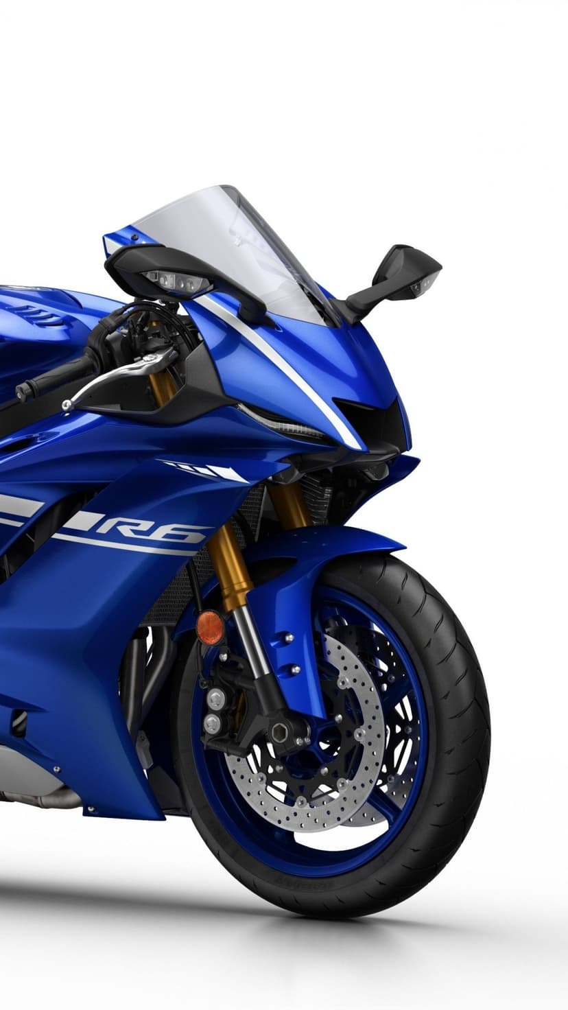 Close-up of a blue Yamaha YZF-R6 motorcycle front fairing, gold forks, and wheel on a white background.