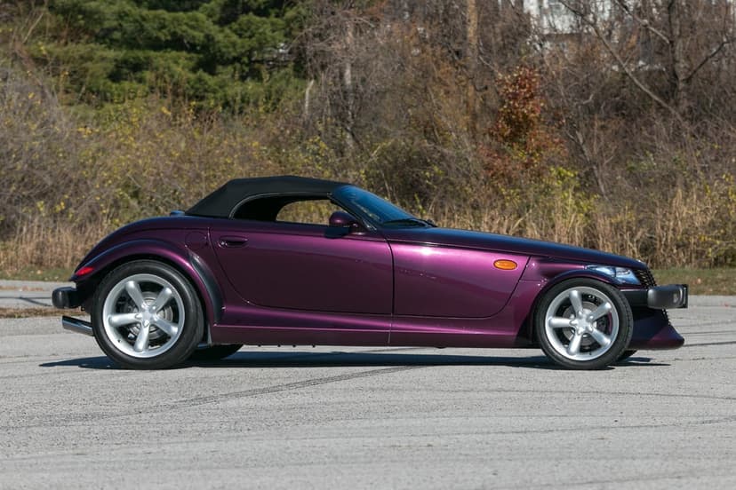 Side profile of a purple Plymouth Prowler convertible sports car with silver wheels on a gray pavement.