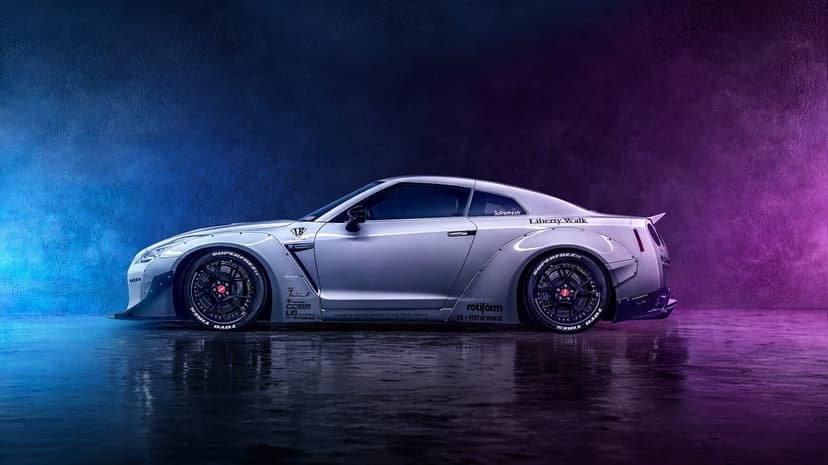 Profile view of a silver widebody Nissan GT-R R35 in a studio with blue and purple neon lighting and floor reflections.