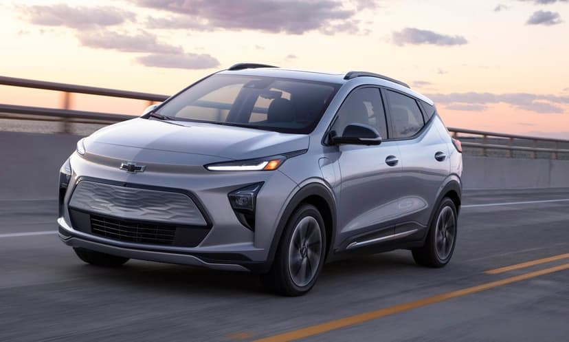 Silver electric crossover car driving on a bridge at sunset with glowing LED lights and motion blur.
