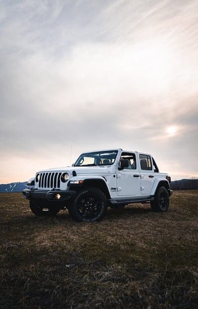 White Jeep Wrangler parked in a field at sunset