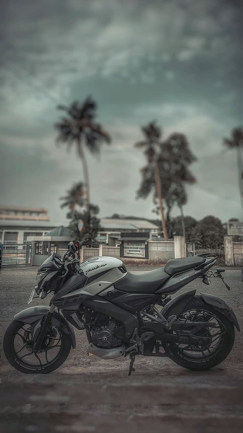 Modern sportbike parked on a city street with tall palm trees and heavy clouds in a high-contrast style.