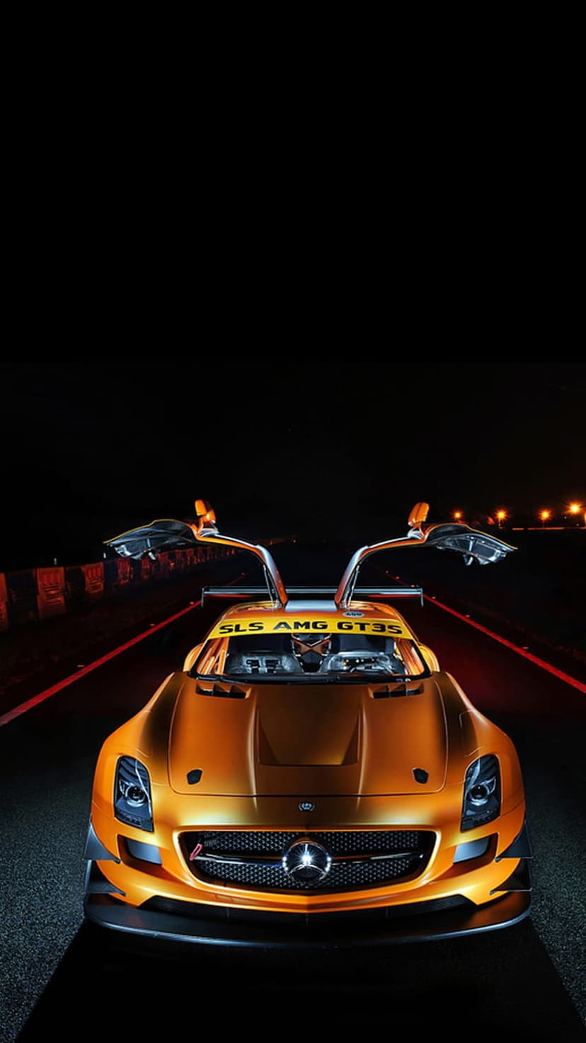 Mercedes-Benz SLS AMG GT3 race car with open gullwing doors on a dark asphalt track illuminated by a red light line.