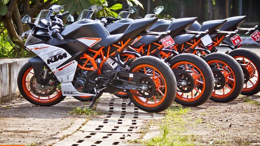 Row of KTM RC motorcycles with vibrant orange wheels and black fairings parked on a stone-patterned path.