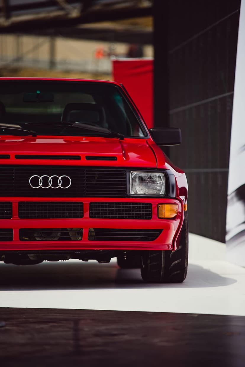 Red Audi Quattro front view with chrome rings logo, mesh grille, and rectangular headlights in a close-up shot