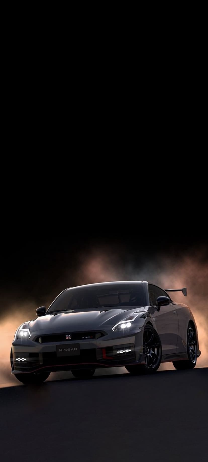 Nissan GT-R R35 drifting through gray smoke with glowing headlights and a large rear spoiler in a dark setting.