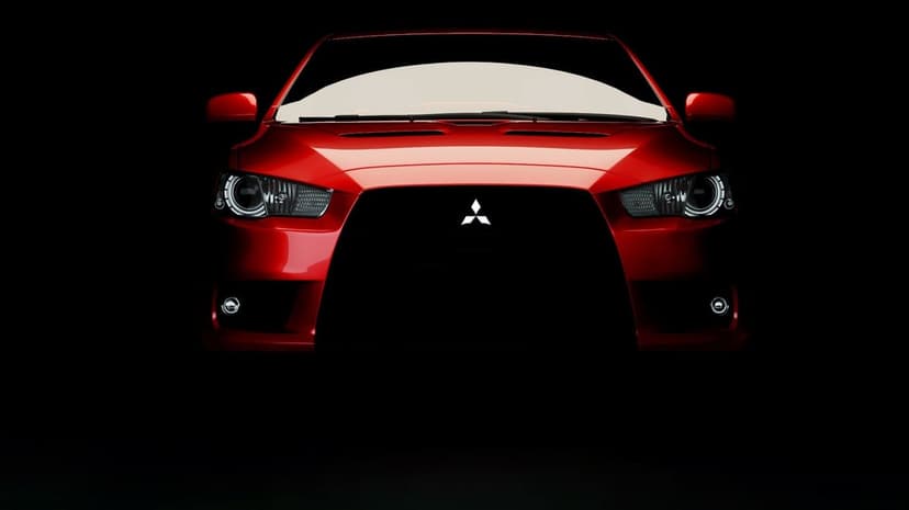 Front view of a red Mitsubishi Lancer Evolution with lit headlights emerging from a dark black background.