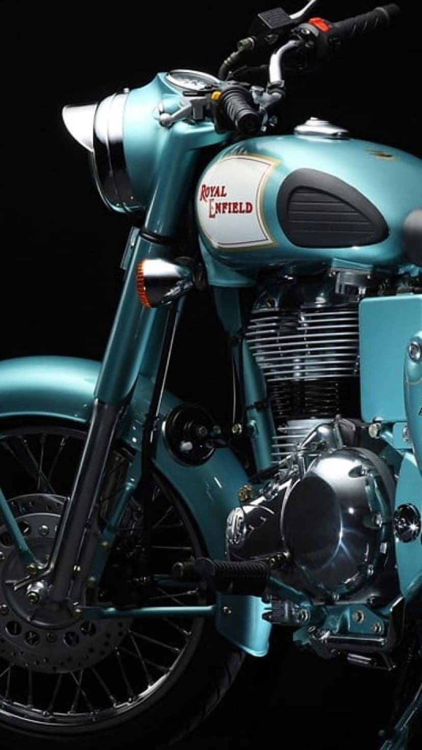 Teal Royal Enfield motorcycle shows a close-up of its chrome engine, emblem, and handlebars in vertical view.