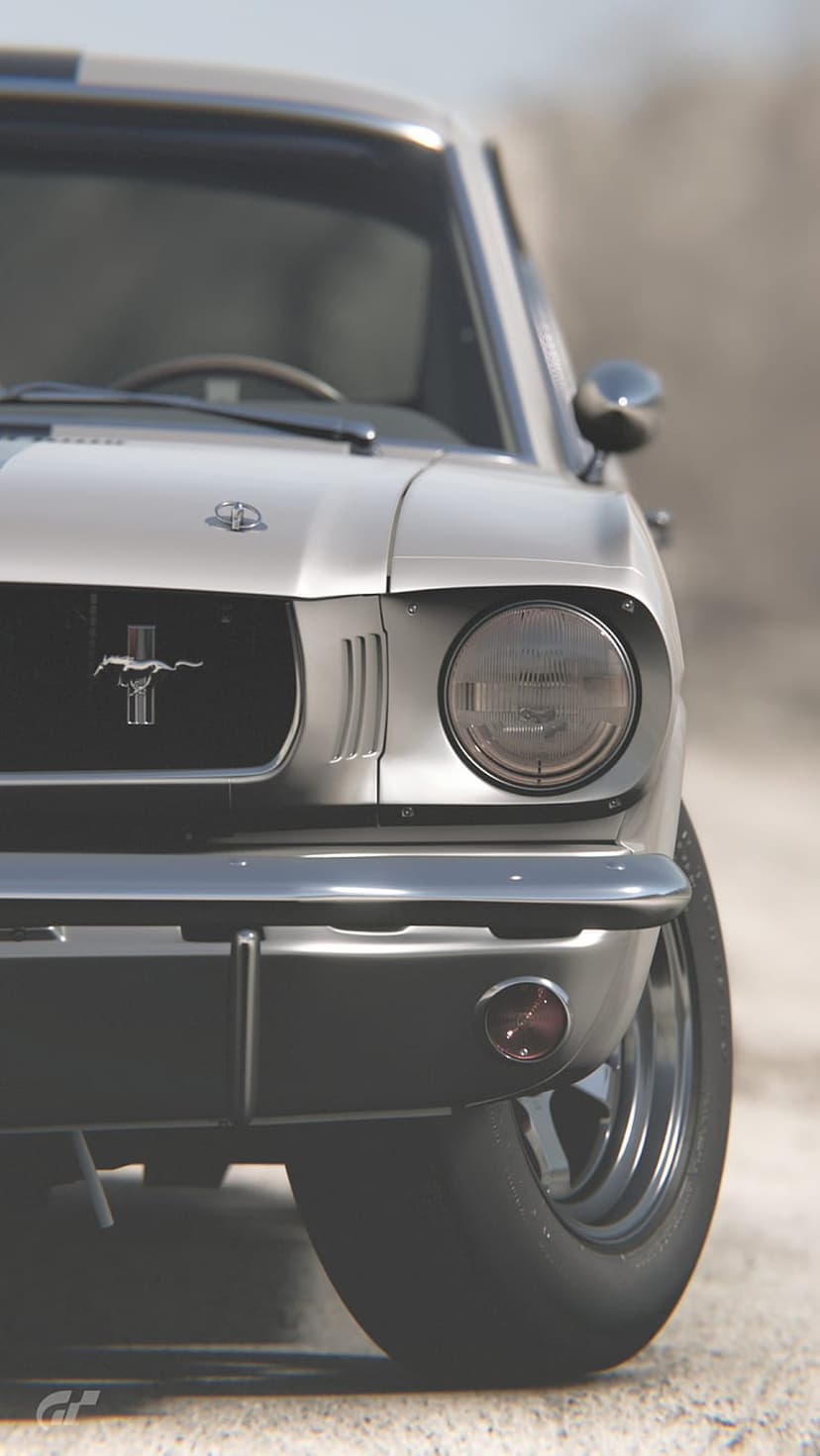 Silver Ford Mustang front grille with a chrome pony emblem, round glass headlight, and polished metal bumper.