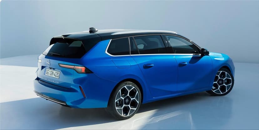 Blue Opel Astra Sports Tourer station wagon with a black roof and silver wheels in a bright studio.