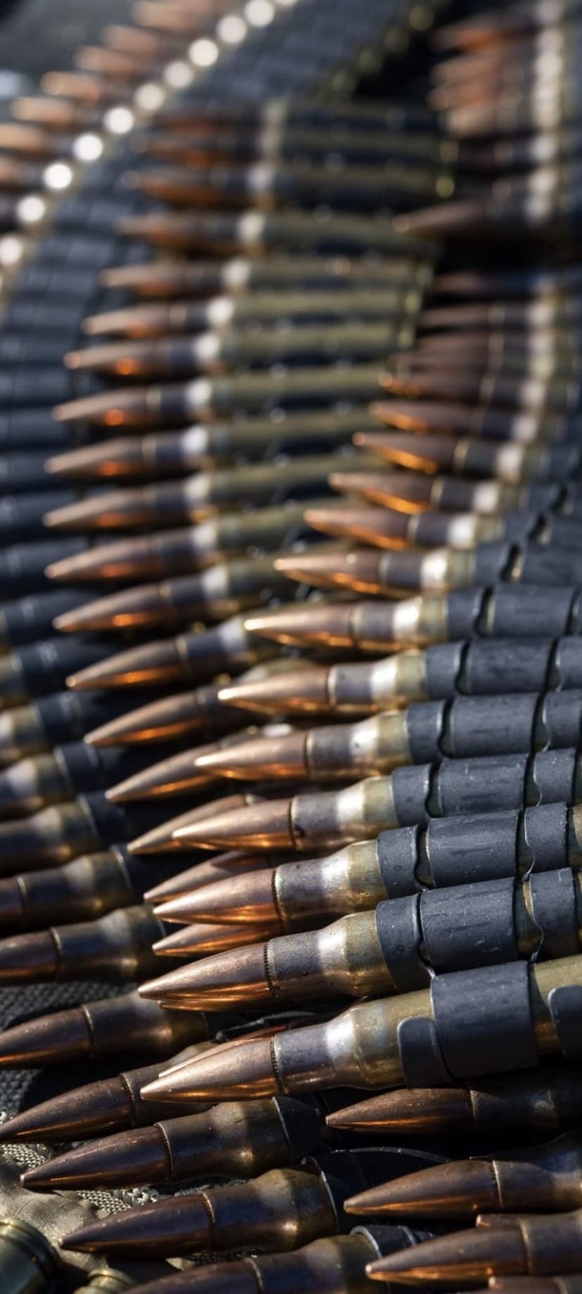 Interlocking brass and dark metal bullets arranged in staggered rows with a shallow depth of field focus.