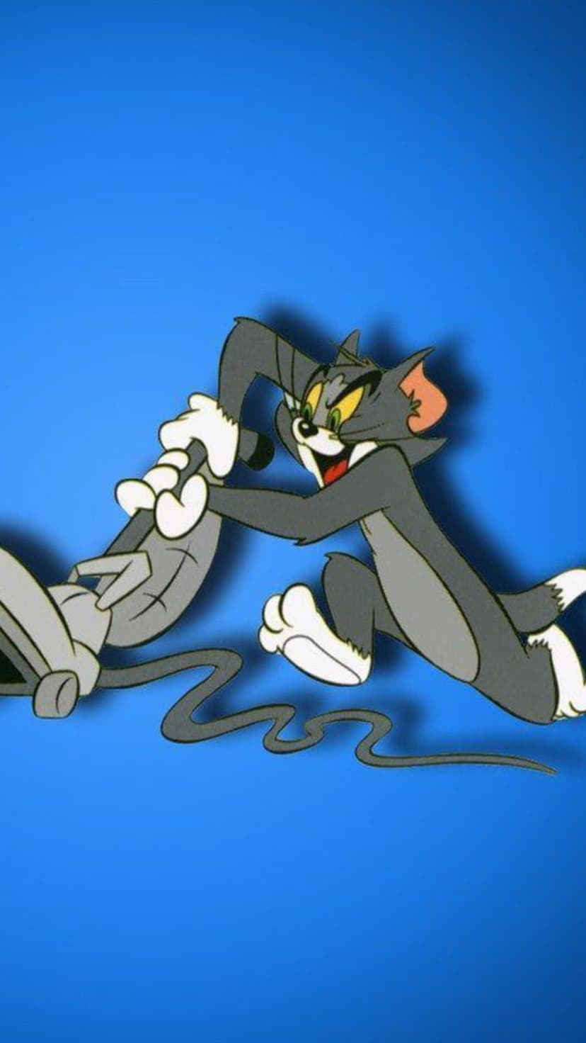 Tom the cat lunges forward with a vacuum cleaner nozzle suctioning Jerry the mouse against a solid blue backdrop.