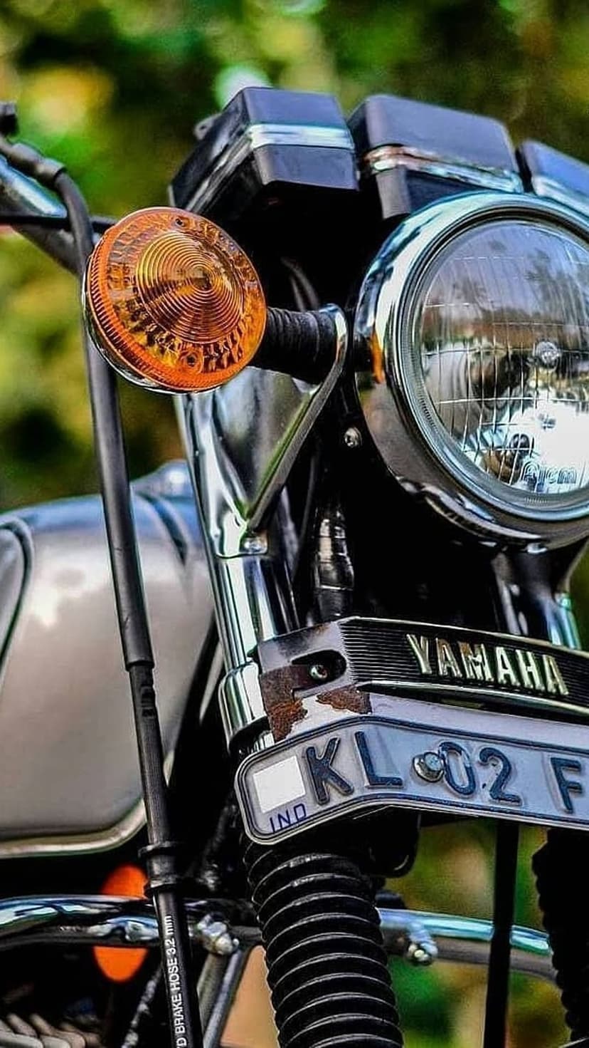 Yamaha motorcycle front view featuring a circular headlight, amber indicator light, and a metal license plate.