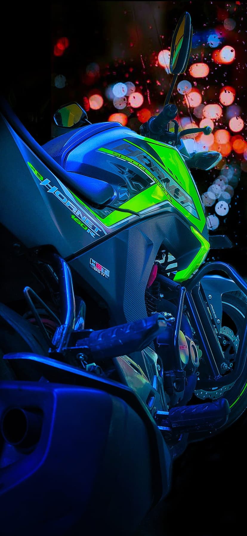 Honda Hornet 160R in neon green and blue with glowing bokeh city lights across the blurred night background.