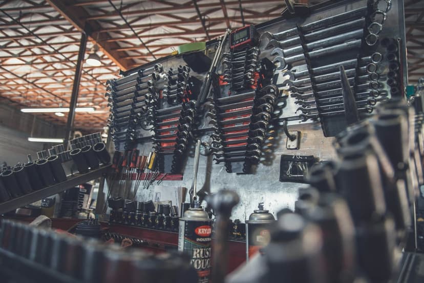 Chrome wrenches and socket sets hang on a dark workshop wall with metallic textures and industrial lighting.