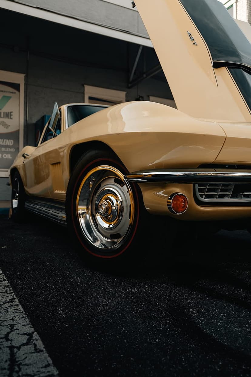 Yellow Corvette Stingray with an open hood and chrome wheels showcases vintage automotive engine details.