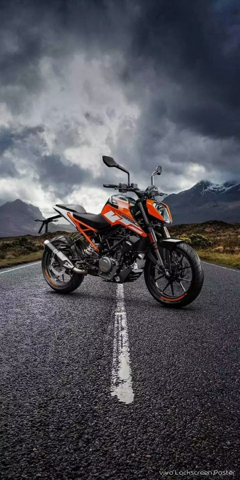 Orange KTM Duke motorcycle parked on a wet asphalt road with mountains and a cloudy sky in the background.