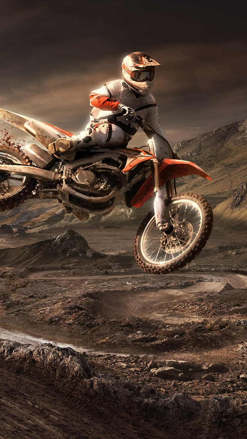 Motocross rider jumping a dirt bike over a dusty desert landscape under a dramatic and cloudy afternoon sky.