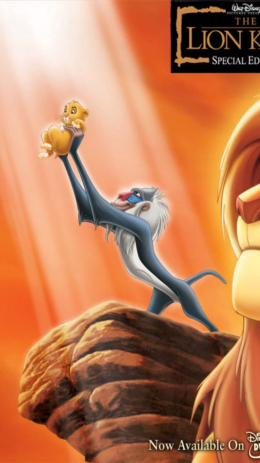 Rafiki holds baby Simba aloft on Pride Rock against a vibrant orange sky with golden sunbeams streaming down.