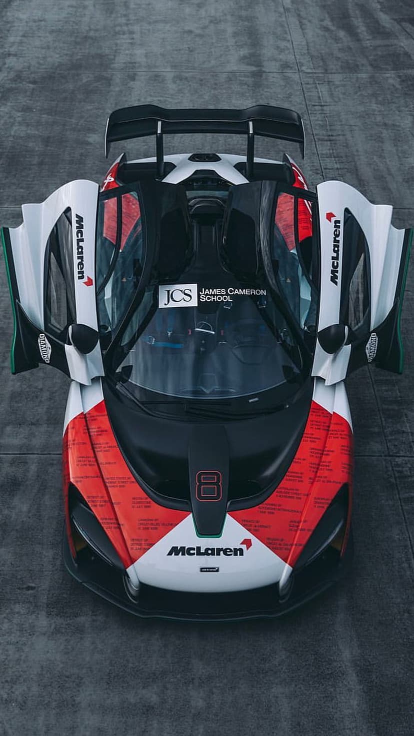 McLaren Senna GTR race car with open dihedral doors and red livery seen from a top-down aerial perspective.