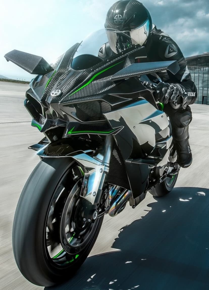 Kawasaki Ninja H2R motorcycle leaning into a track turn with a rider in a full racing suit and helmet.
