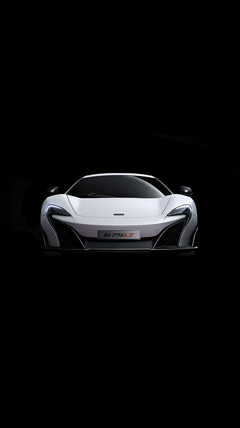 White McLaren 675LT supercar with aggressive aerodynamic vents and a 675LT badge centered on a dark background.