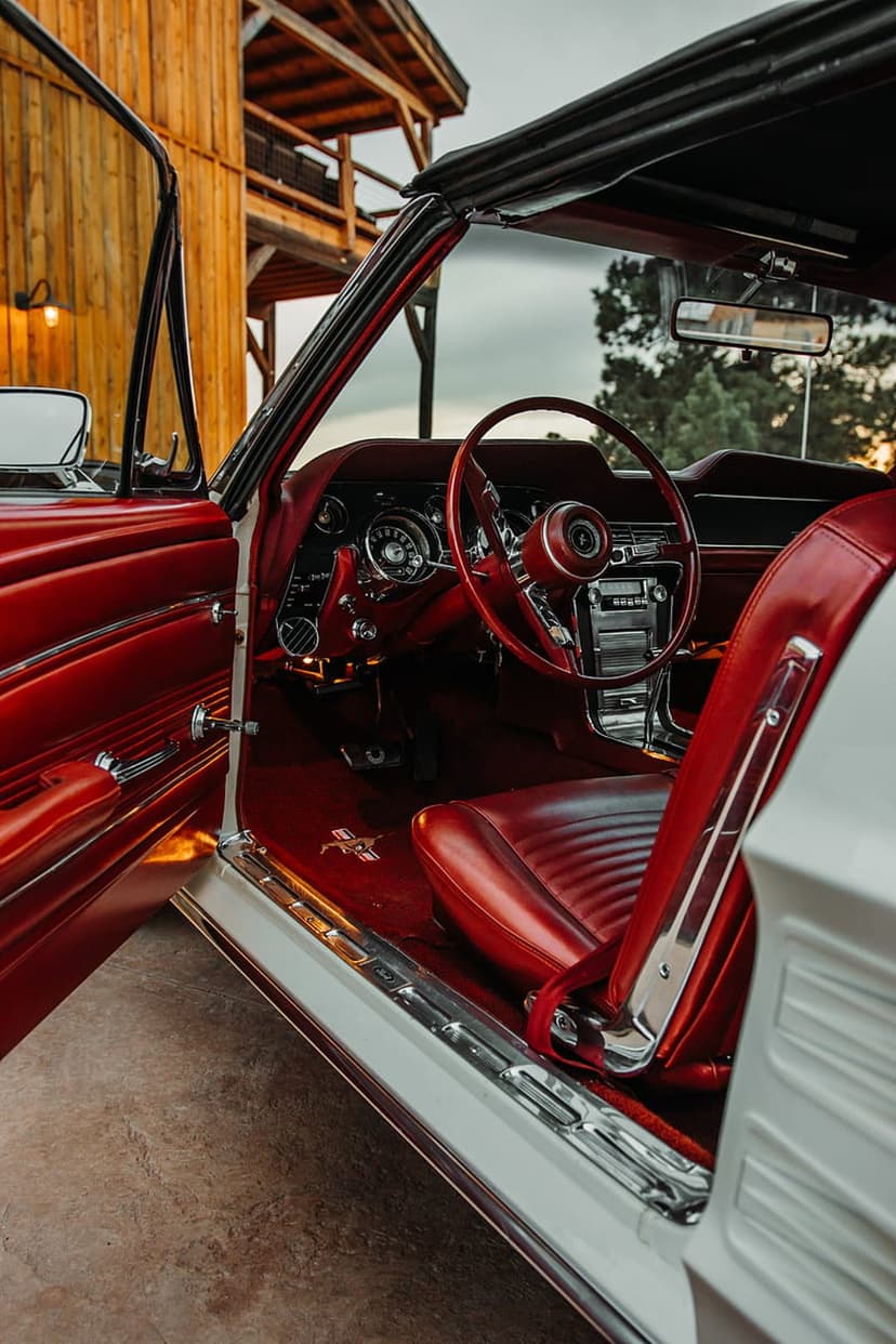 Red leather seats and a vintage steering wheel inside a classic convertible with chrome dashboard gauges.
