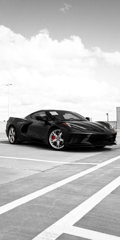 Sleek Black Corvette C8 Parked Under Dramatic Clouds