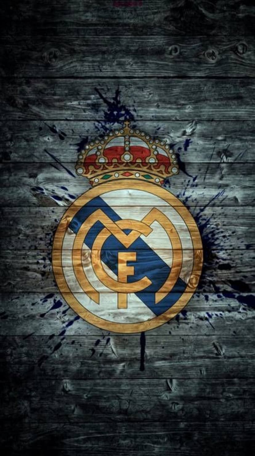 Real Madrid crest with a gold crown on a dark weathered wood background with subtle blue paint splatters.