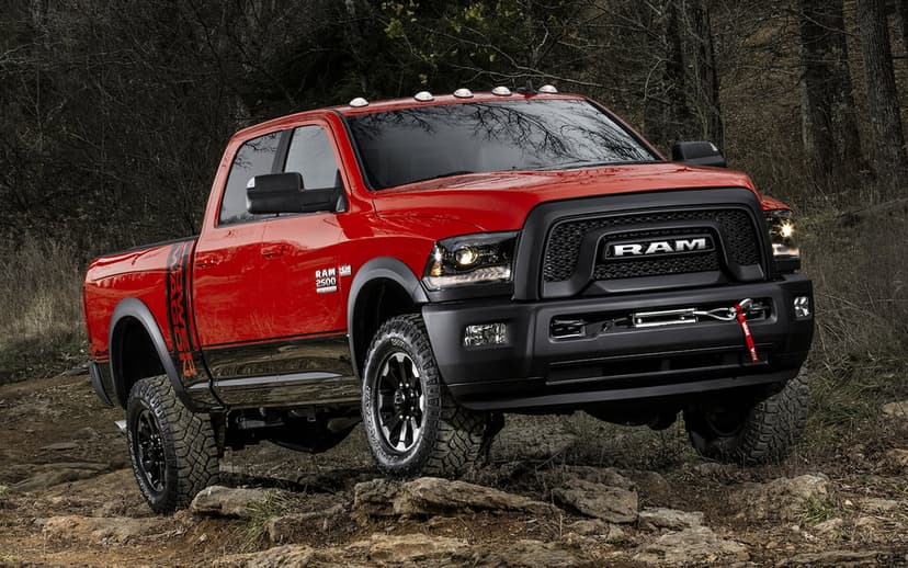 Red Ram 2500 Power Wagon off-road truck with a black winch on a rocky hill in a dark forest setting.