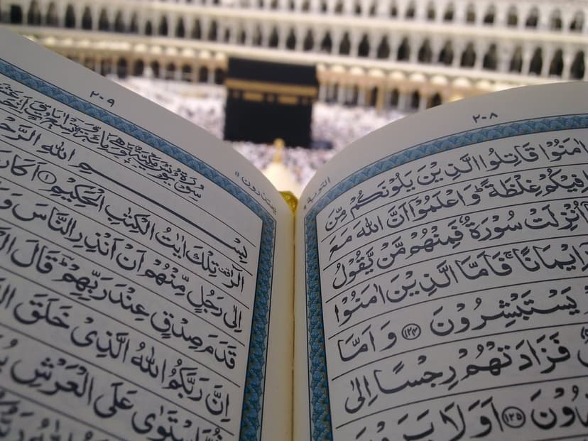Open Quran with Arabic script in front of the Kaaba in Mecca, designed as a vertical religious phone background.