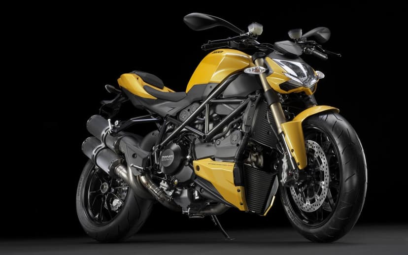 Yellow Ducati Streetfighter motorcycle with a black trellis frame and gold forks against a dark studio background.