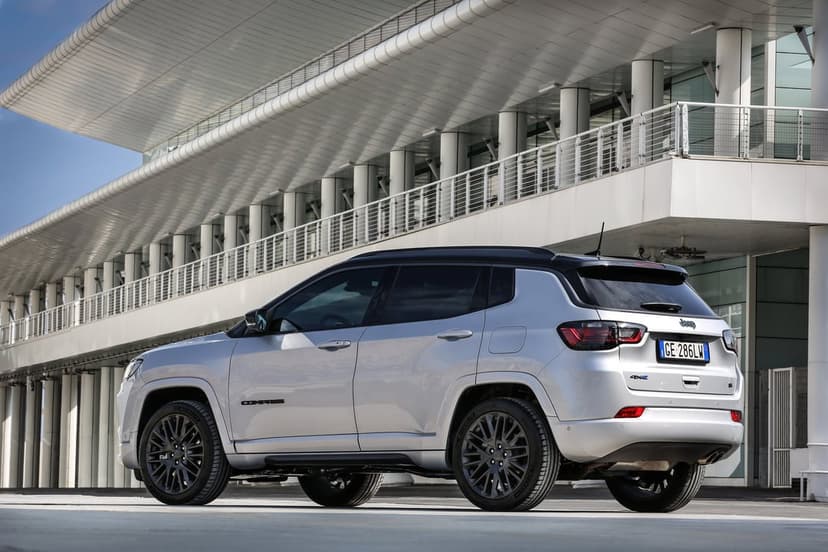Silver Jeep Compass SUV with a black roof and dark wheels parked in front of a modern white building.
