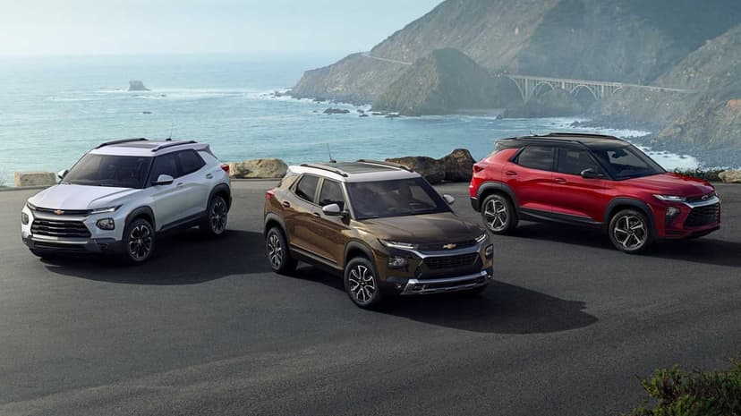 Three Chevrolet Trailblazer SUVs parked on a coastal road with a bridge and ocean in the background.