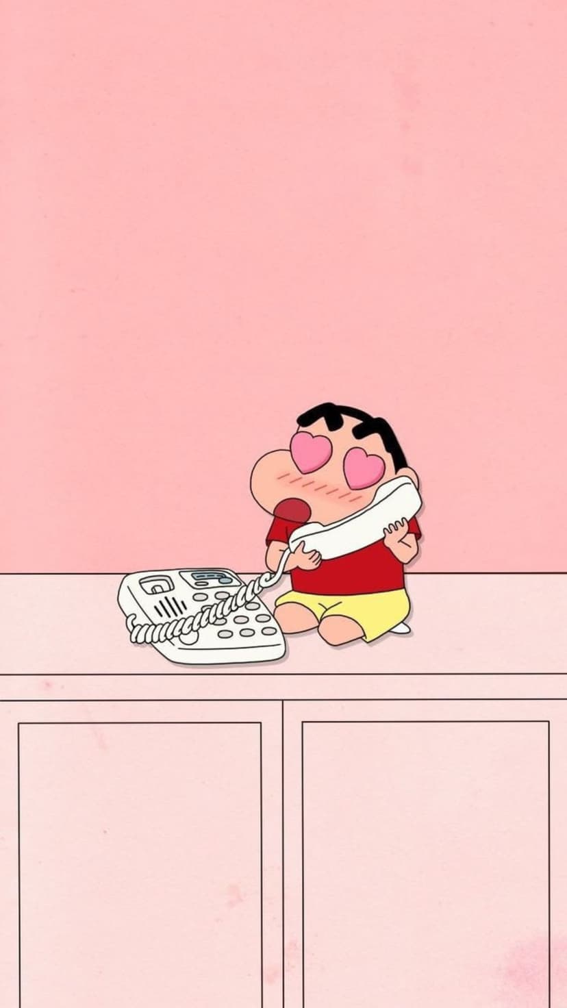 Shin Chan holding a landline phone receiver with pink heart eyes against a solid light pink background.