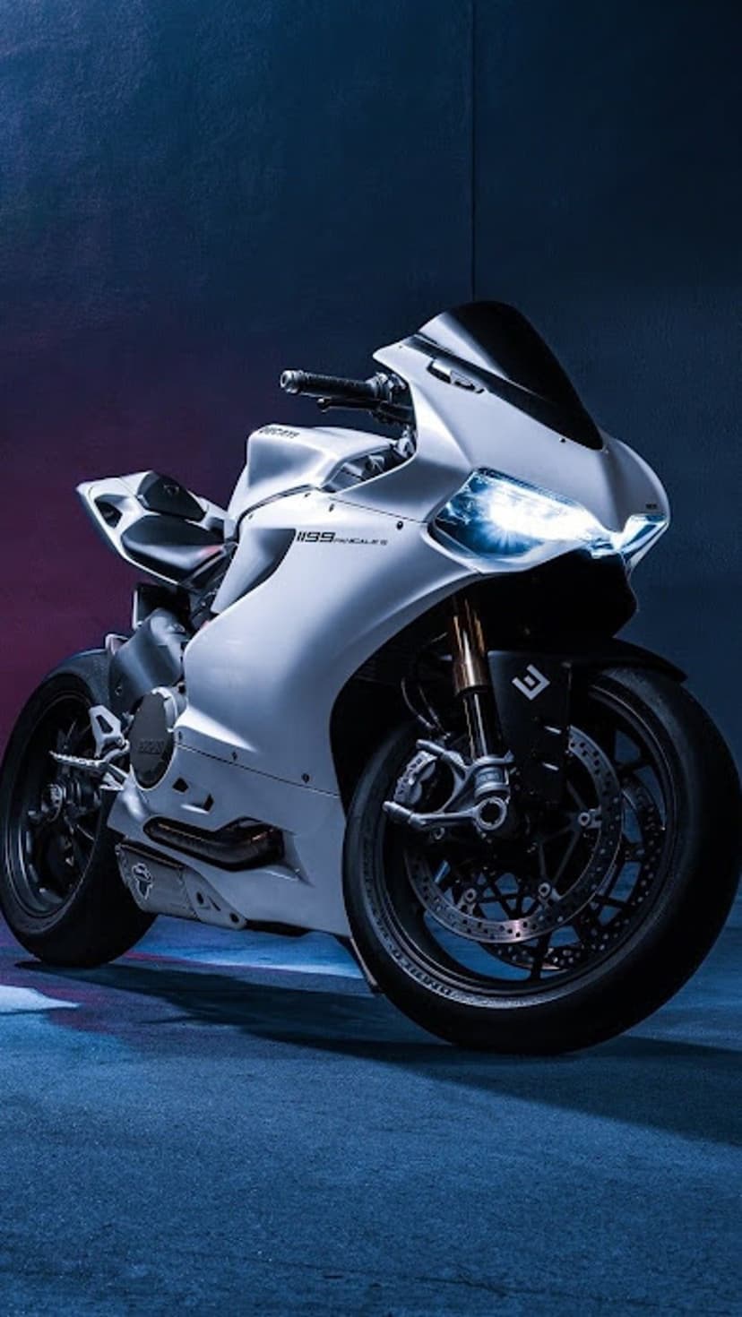 White Ducati 1199 Panigale motorcycle with glowing LED headlights against a dark blue and purple studio background.