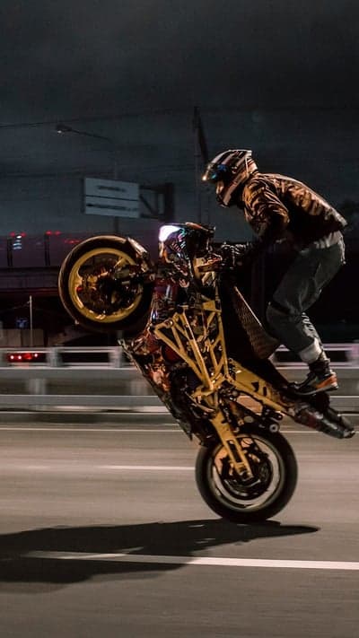 Motorcyclist Performs Wheelie on Street at Night
