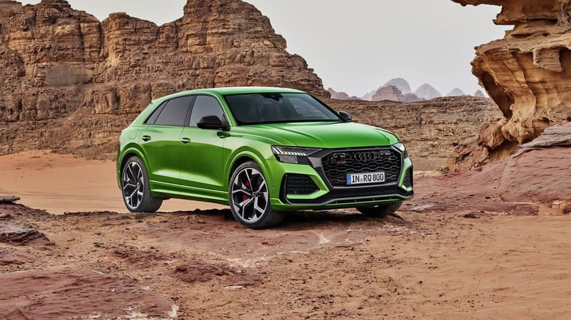 Green Audi RS Q8 luxury SUV parked on a rocky desert plateau with massive sandstone formations in the background.