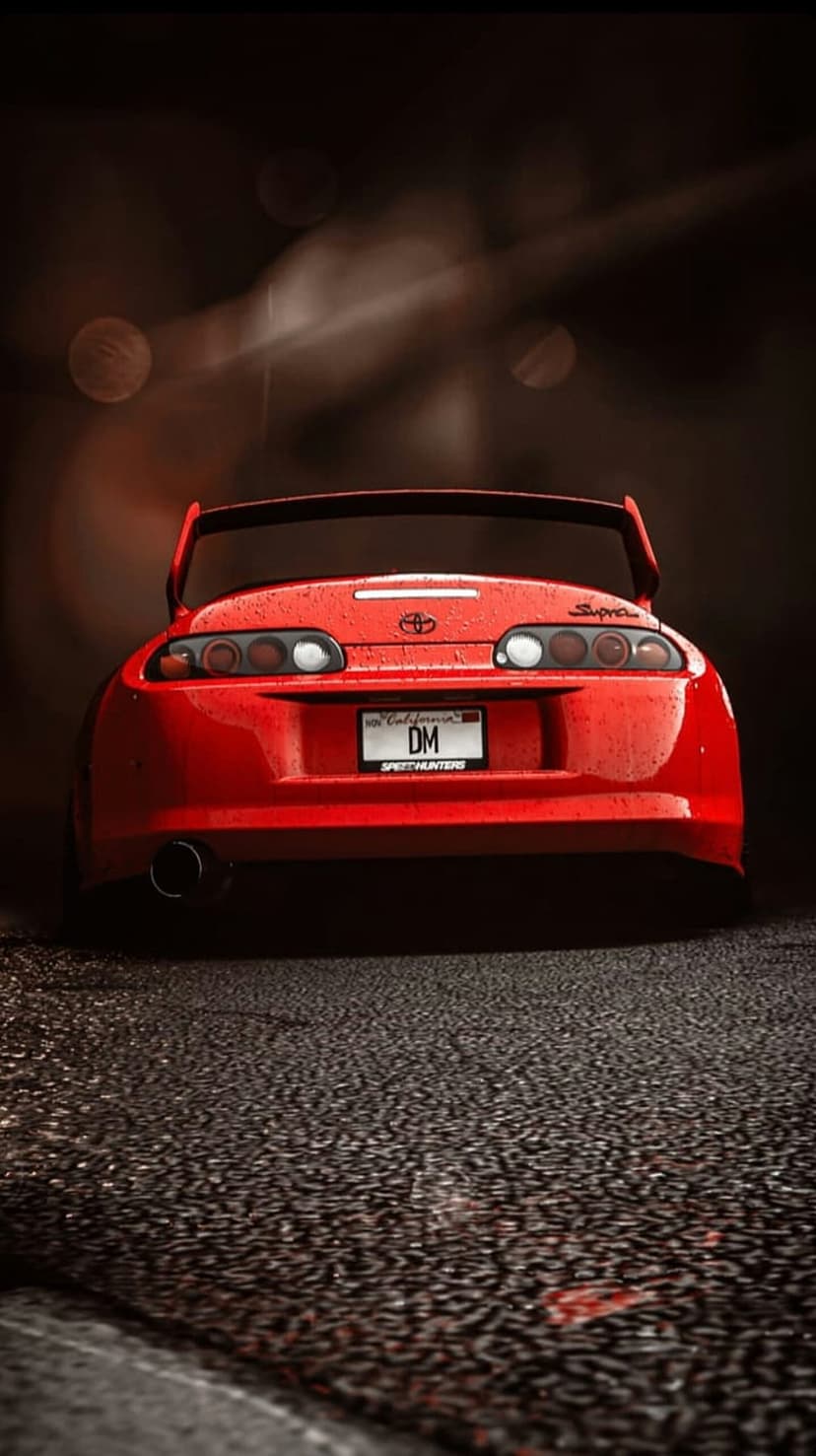 Red Toyota Supra rear view with glowing taillights on wet asphalt under soft night city bokeh lights.