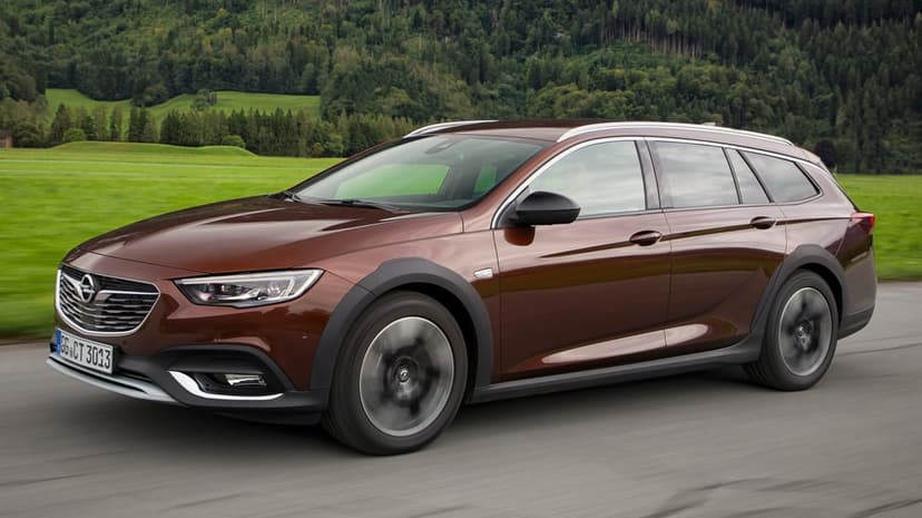 Brown Opel Insignia Country Tourer driving on a mountain road with blurred wheels and green forest background.