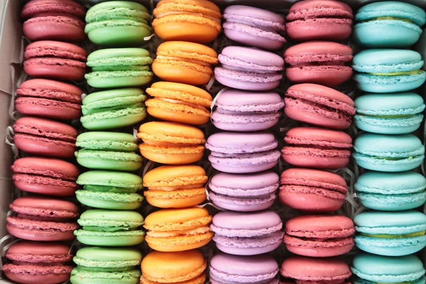 Pastel French macarons organized in neat rows inside a white box viewed from a top-down perspective.