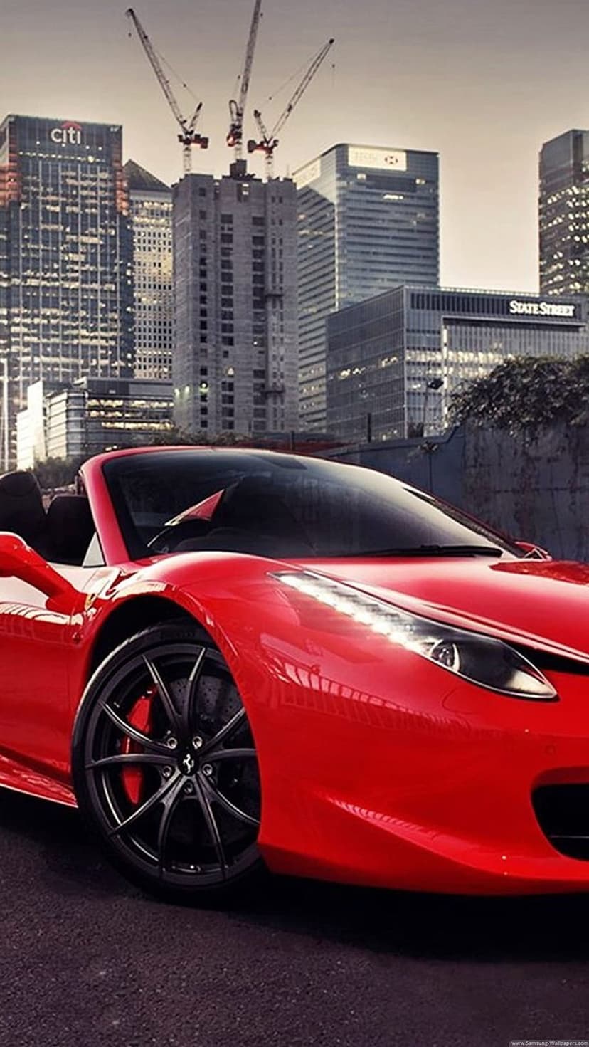 Red Ferrari convertible with black rims parked on wet asphalt in front of modern city skyscrapers and cranes.
