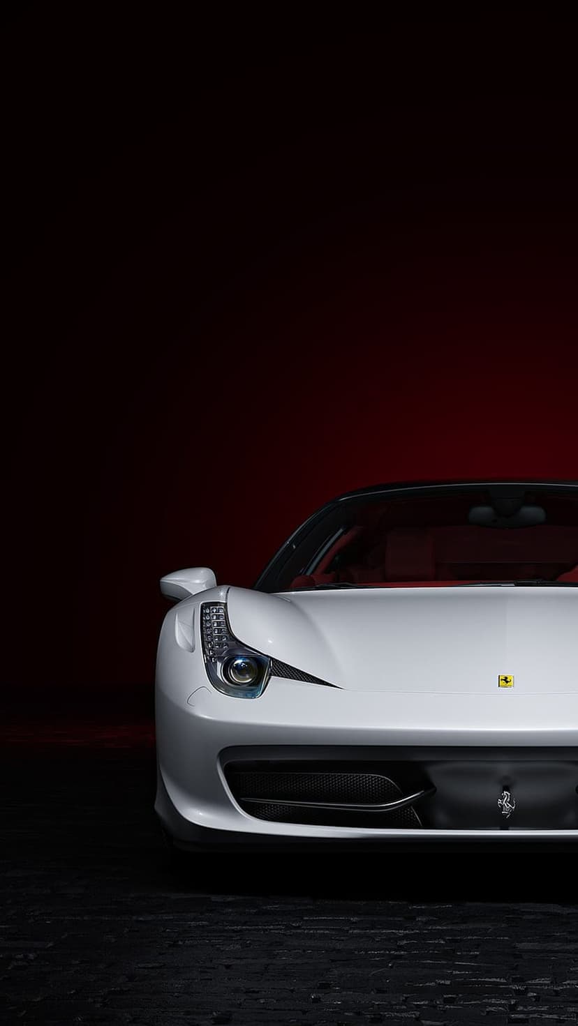 White Ferrari 458 Italia headlight and front bumper curves set against a solid crimson red background.