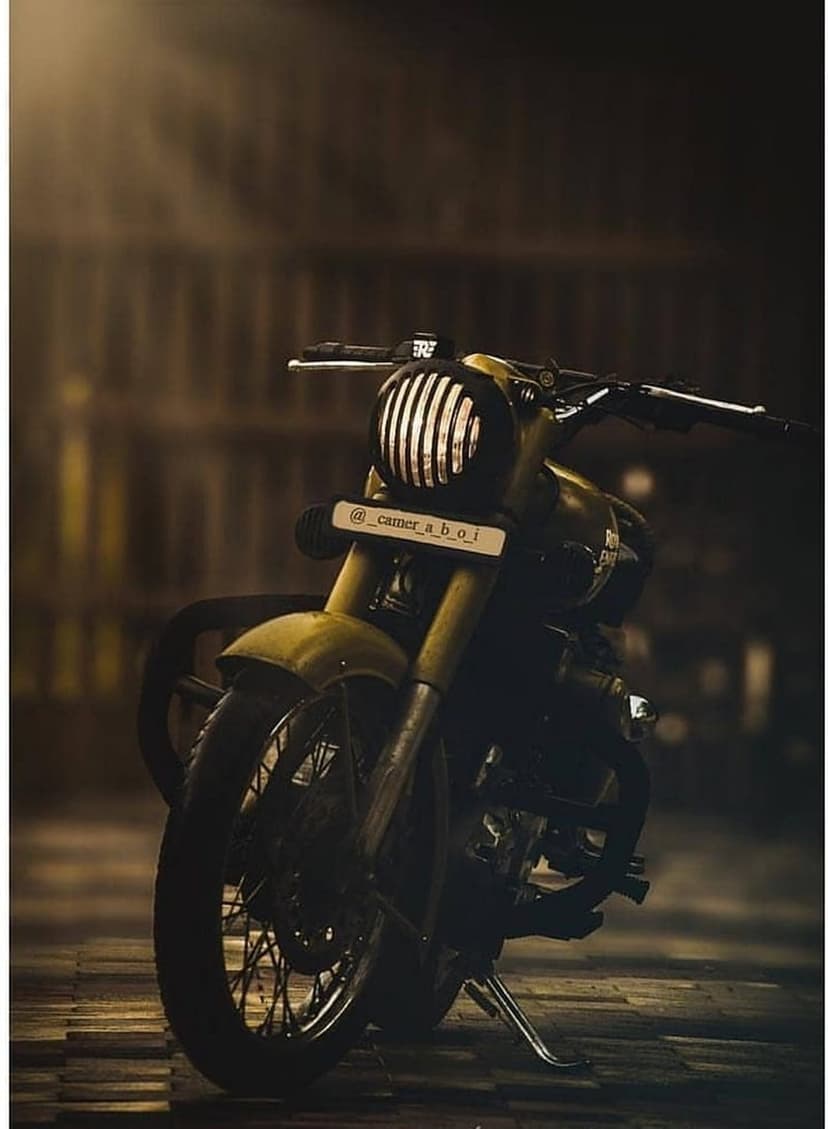 Yellow Royal Enfield motorcycle close-up featuring a ribbed glass headlight and metallic front fork assembly.