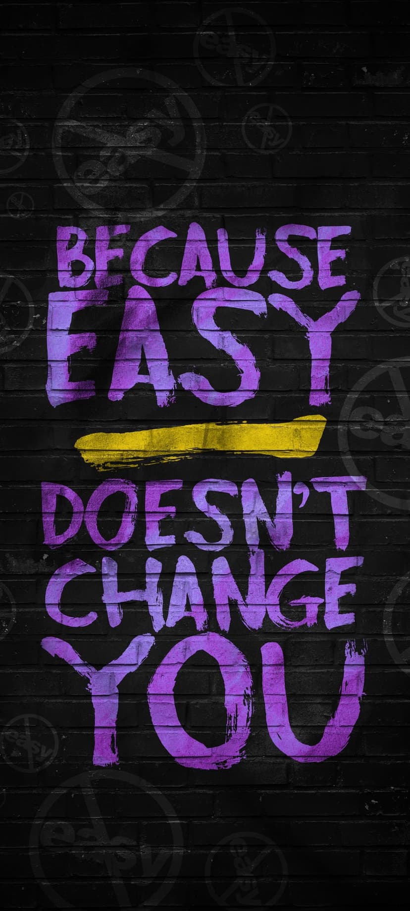 Purple graffiti letters on black bricks read BECAUSE EASY DOESN'T CHANGE YOU with a yellow strike through.