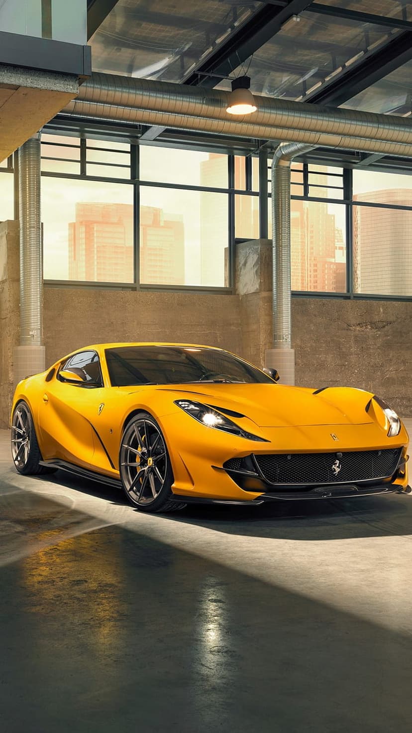 Yellow Ferrari 812 Superfast supercar in a modern garage with large windows and a distant cityscape view.