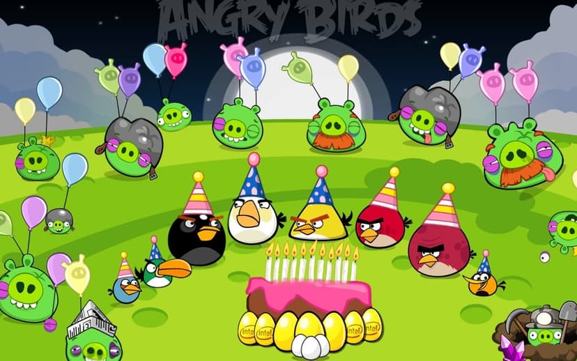 Angry Birds characters and green pigs wearing party hats around a birthday cake under a full moon.
